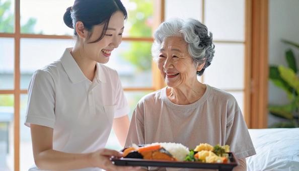 高齢女性と女性介護士の穏やかな食事風景 高齢女性と女性介護士の穏やかな食事風景の写真