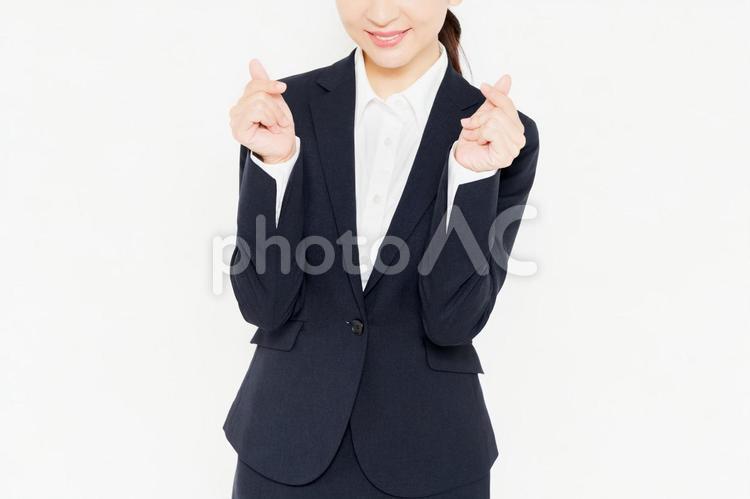 白背景の前に立って、手でハートの形を作るスーツを着たビジネスウーマン 女性,ハート,気持ちの写真素材