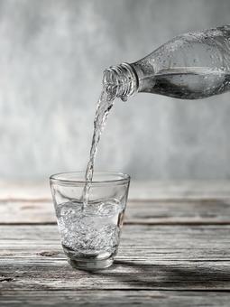ペットボトルからコップへ水を注ぐ ペットボトルからコップへ水を注ぐの写真