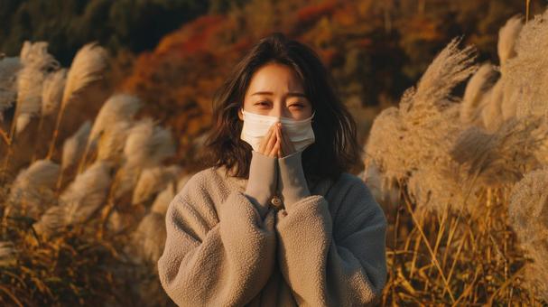 秋風に揺れるススキとマスク姿の女性 秋風に揺れるススキとマスク姿の女性の写真
