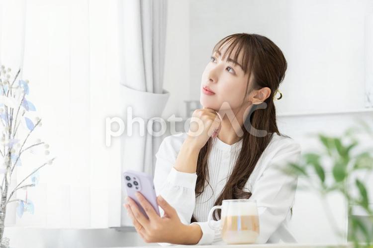 スマホを使いながら考えごとをする女性 女性,人物,スマホの写真素材