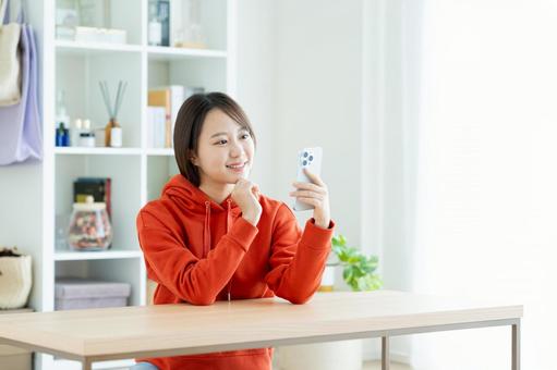 リビングでスマホを使う若い女性 リビングでスマホを使う若い女性 スマホ,女性,家の写真素材