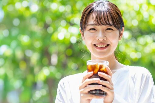 アイスコーヒーを手に微笑む女性 アイスコーヒーを手に微笑む女性の写真