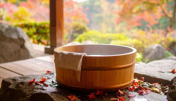 紅葉した落葉が舞い落ちる露天風呂の風呂桶 紅葉した落葉が舞い落ちる露天風呂の風呂桶の写真