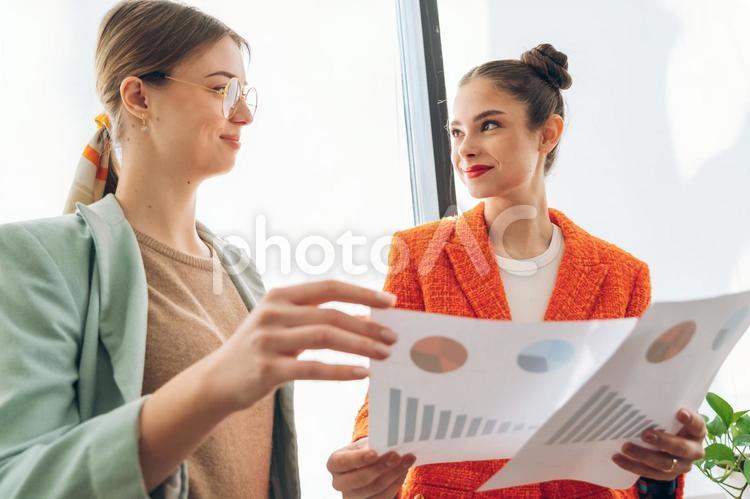 資料のグラフを見て話す2人の女性 ビジネス,ビジネスウーマン,女性の写真素材