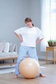 足でボールを挟みポーズする女性の写真