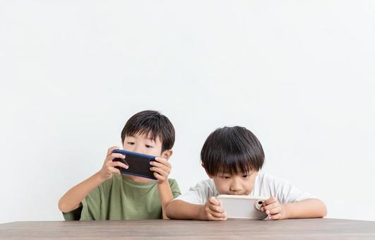 スマホに夢中になる子ども スマホに夢中になる子どもの写真