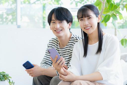リビングでスマホを見る若いカップル リビングでスマホを見る若いカップル 夫婦,カップル,リビングの写真素材