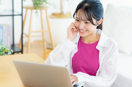 自宅でノートパソコンを操作する若い女性 若い女性,ノートパソコン,笑顔の写真素材