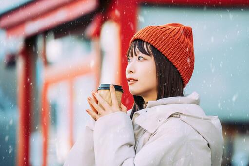 雪の降る冬の街角に立つ笑顔の女性 冬,雪,女性の写真素材