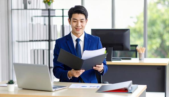 PCと書類を前に笑顔で話すビジネスマンの写真