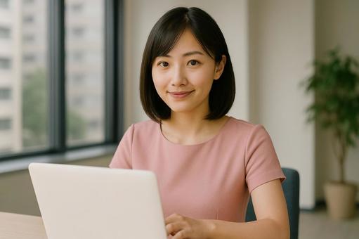  A smiling woman operating a computer by the window , office, remote work, work at home, JPG