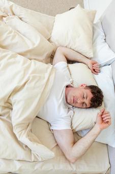 ベッドで両手を上げて寝ている男性 縦,男性,外国人の写真素材