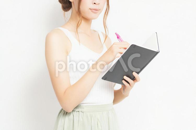 ノートとペンを持つ若い女性 女性,ノート,ボールペンの写真素材