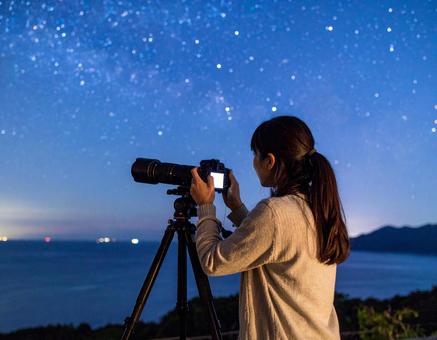 三脚を使って星空を撮影する女性 三脚を使って星空を撮影する女性の写真