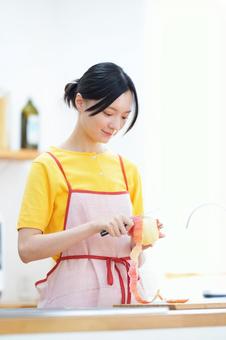 微笑みながら皮むきをしている女性 女性,微笑む,リンゴの写真素材