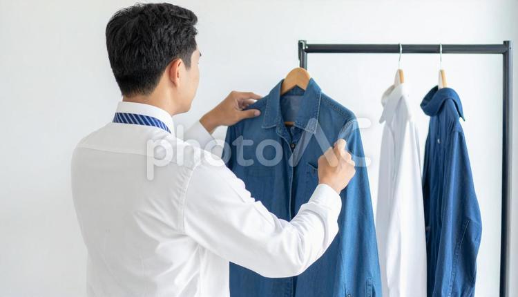 ハンガーにかかる私服を取るビジネスマン カジュアル,プライベート,ハンガーの写真素材