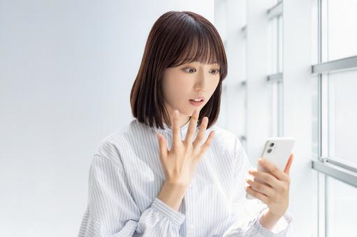スマホの画面を見て驚く女性 スマホの画面を見て驚く女性 女性,スマホ,スマートフォンの写真素材