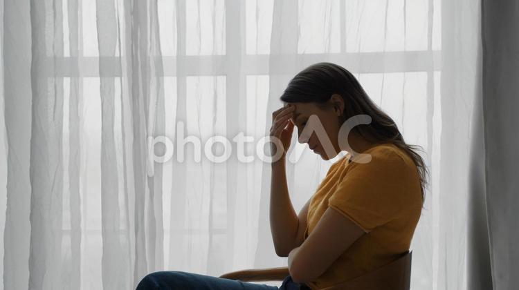おでこに手を置いて考える女性 女性,悩み,考えるの写真素材