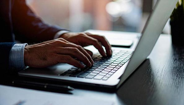 デスクワーク　パソコンに両手で入力する手の写真