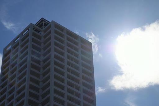 青空と雲と白く輝く太陽と高層ビルの街並み 青空と雲と白く輝く太陽と高層ビルの街並みの写真