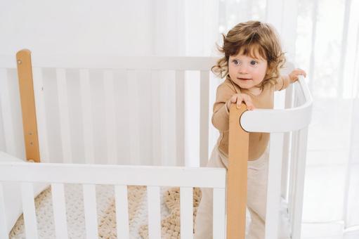 1人でベッドの柵に掴まり立っている子供 1人でベッドの柵に掴まり立っている子供 赤ちゃん,かわいい,ベビーベッドの写真素材