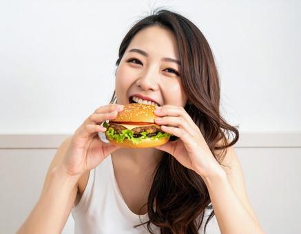 おいしそうにハンバーガーにかじりつく女性 おいしそうにハンバーガーにかじりつく女性の写真