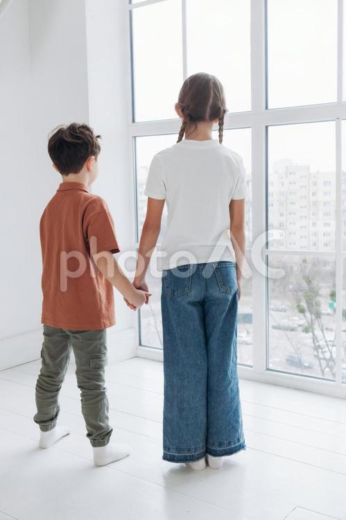 窓辺で手を繋ぐ仲良しな姉弟 姉弟,女の子,男の子の写真素材