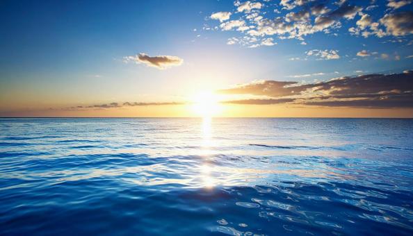 水面に映る朝日　水平線　青い海の写真