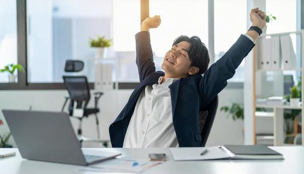 仕事が終わり達成感で背伸びをする社員 仕事が終わり達成感で背伸びをする社員の写真