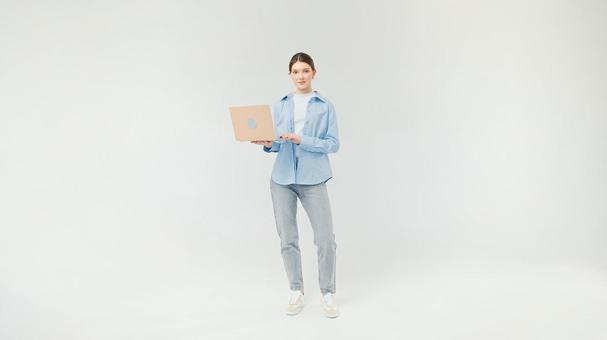 パソコンを持ちカメラ目線のカジュアルな女性 パソコンを持ちカメラ目線のカジュアルな女性の写真
