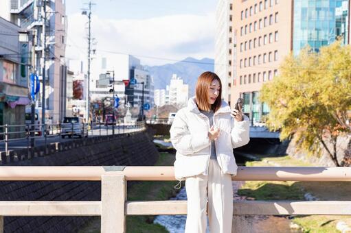 橋の上でスマホを操作する女性 橋,女性,スマホの写真素材