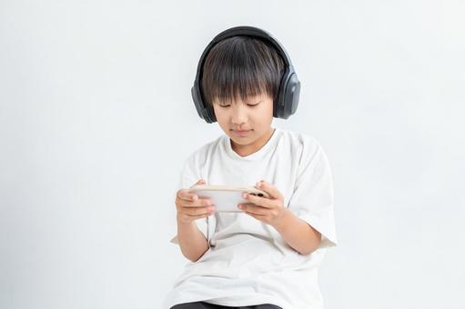 ヘッドフォンをしてゲームする男の子 ヘッドフォンをしてゲームする男の子 ヘッドフォン,男の子,白背景の写真素材