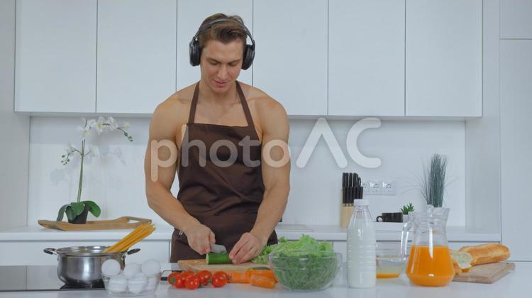 微笑みながら野菜を切る男性 男性,マッチョ,料理の写真素材