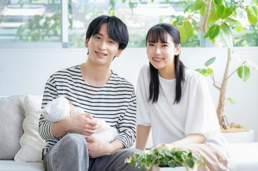 リビングで赤ちゃんを抱く若い家族 リビングで赤ちゃんを抱く若い家族 家族,親子,赤ちゃんの写真素材