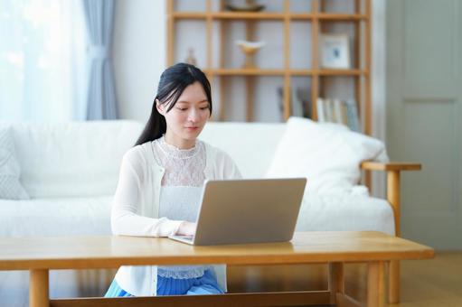 リビングでパソコン作業をする女性 女性,ノートパソコン,座るの写真素材