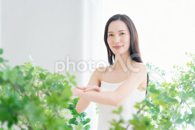 緑の中でスキンケアをする若い女性 ビューティー,女性,スキンケアの写真素材