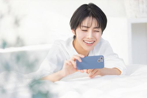 A woman operating a smartphone while lying down, JPG A woman operating a smartphone while lying down, JPG