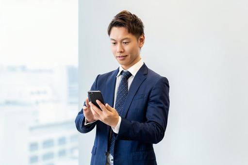 オフィスでスマホを使う男性ビジネスマン オフィスでスマホを使う男性ビジネスマン 男性,スマホ,スマートフォンの写真素材