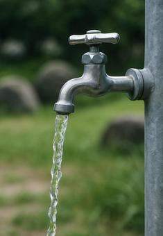 屋外の水道の蛇口から水が流れる瞬間 屋外の水道の蛇口から水が流れる瞬間の写真