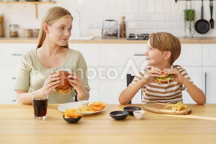 ハンバーガーを持って見つめる親子 女性,男の子,親子の写真素材