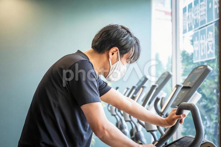 エアロバイクで運動する男性（マスク） エアロバイク,マスク,有酸素運動の写真素材