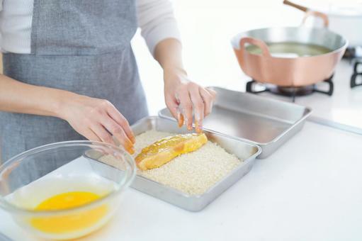 卵の付いた豚肉をパン粉の上にのせた手 卵の付いた豚肉をパン粉の上にのせた手の写真