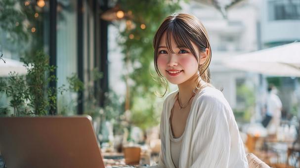 緑豊かなカフェでノートPCを使用する女性の写真