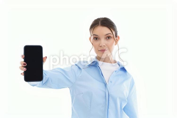 カメラ目線でスマホの画面を見せる女性 女性,スマートフォン,持つの写真素材