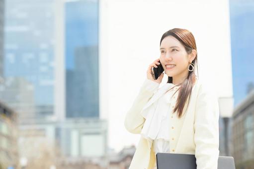 ビル街で電話をする女性 ビル街で電話をする女性 スーツ,女性,笑顔の写真素材
