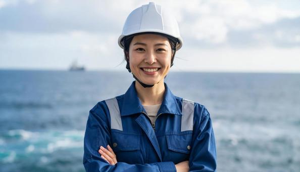 青空と海の背景に笑顔の作業服の若い女性 青空と海の背景に笑顔の作業服の若い女性の写真