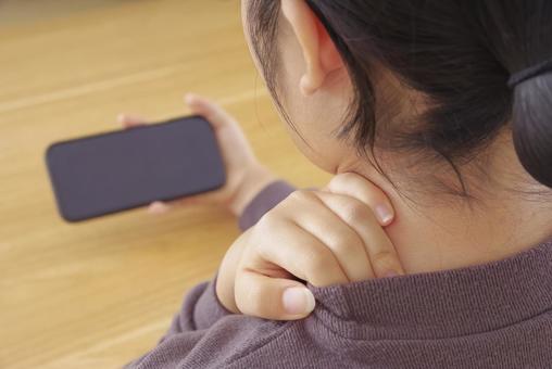 首・肩が痛そうにスマホを操作している女性 スマホ首,ストレートネック,スマホの写真素材