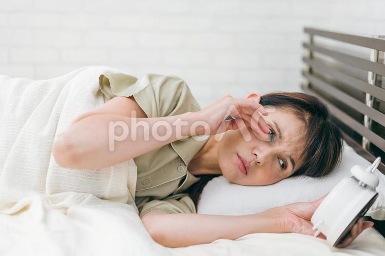 寝坊するミドル世代の女性（眠い） 遅刻,目覚め,寝起きの写真素材