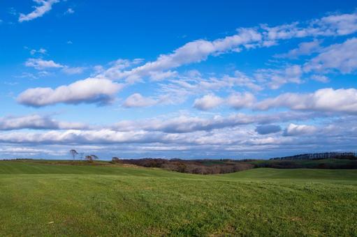 雲が広がる青空の下で穏やかに連なる緑の丘 丘,牧草地,緑の写真素材
